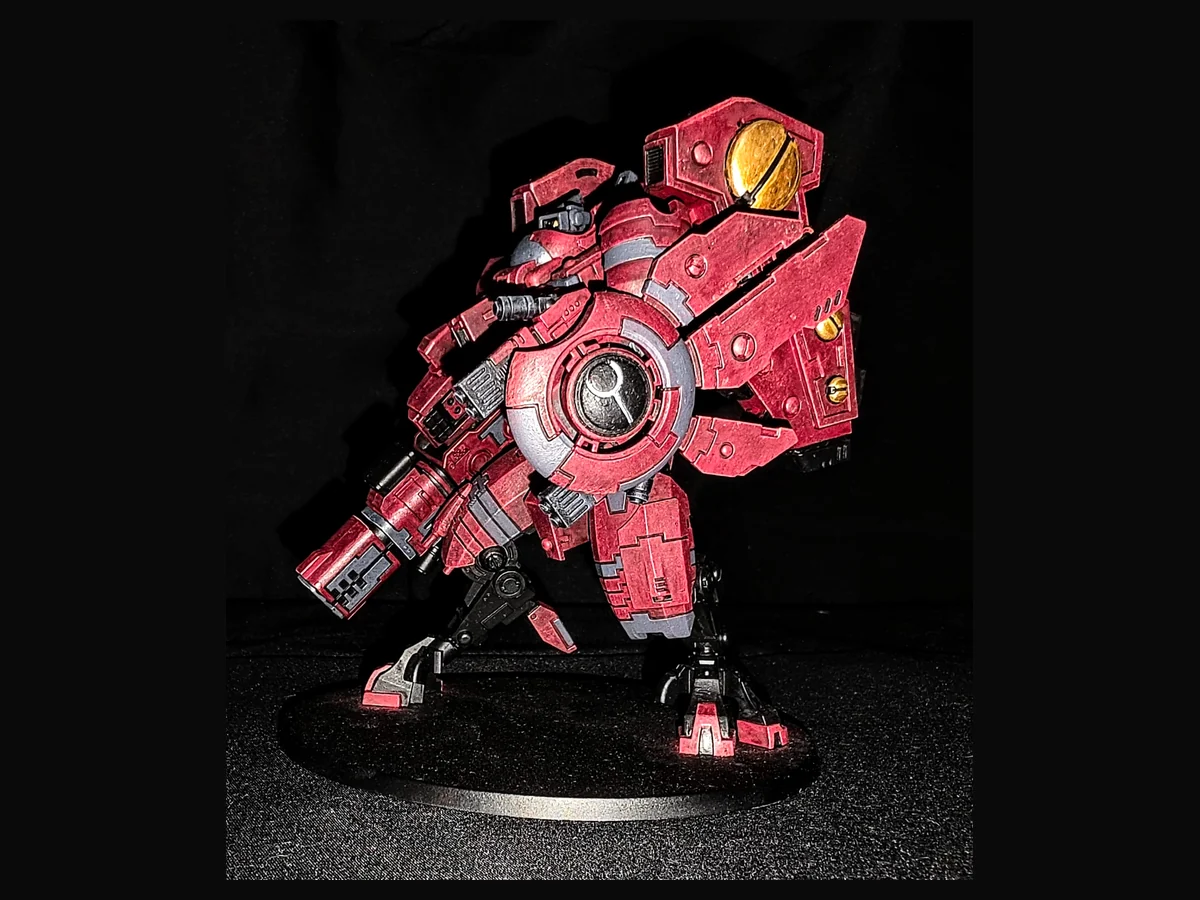 Painted red T’au battlesuit miniature.