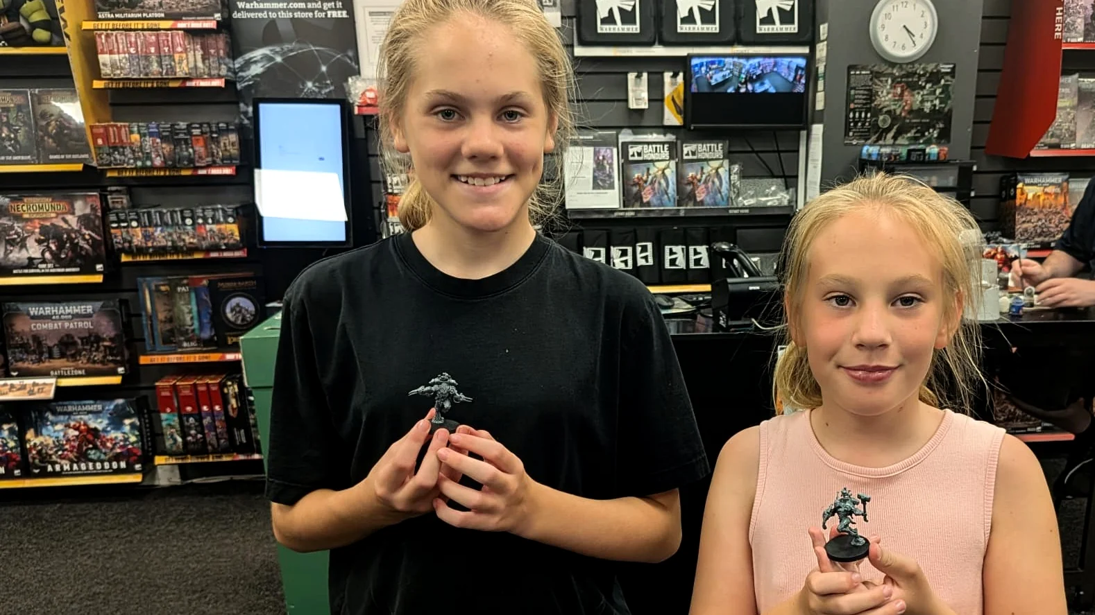 Young hobbyists holding miniatures they built during a Warhammer hobby session.