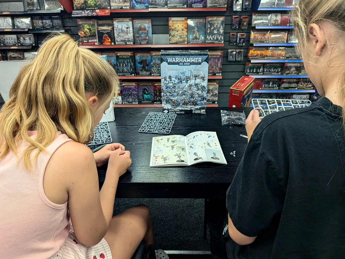 Young hobbyist building a miniature during a supported hobby-store visit.