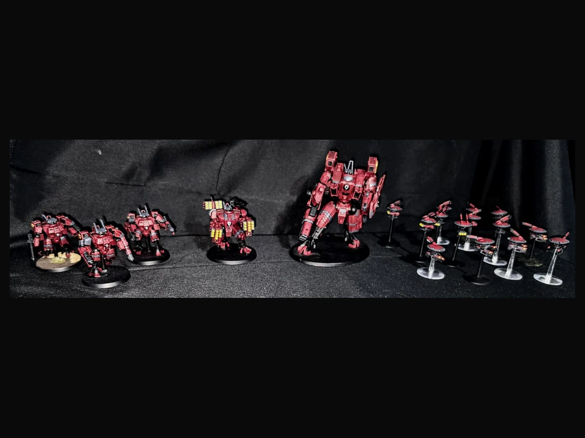 Collection of painted red T’au miniatures and vehicles.