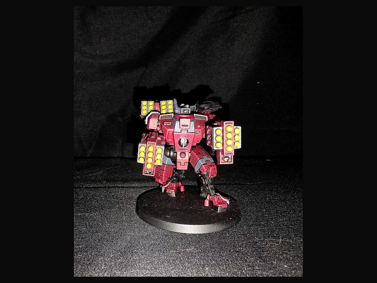 Painted red T’au battlesuit with yellow missile details.